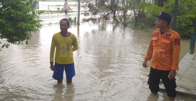 Anggota BPBD Bojonegoro saat berada di halaman rumah salah satu warga setempat yang terendam air.