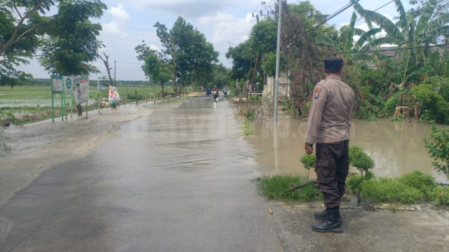 Anggota Polsek Baureno ketika berada di jalan poros utama Kecamatan Baureno - Kepohbaru, yang tergenangi air untuk mengatur arus lalulintas.