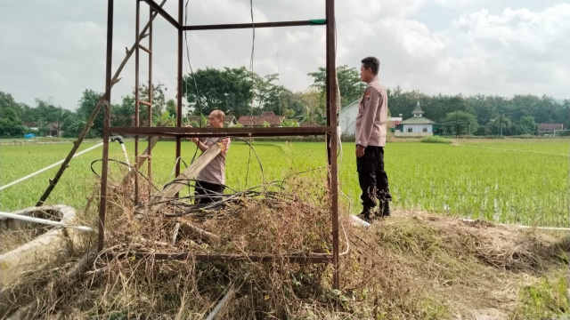 Anggota polisi saat berada di sawah tempat kejadian perkara Kades Gombang ditemukan meninggal dunia diduga kesetrum listrik.