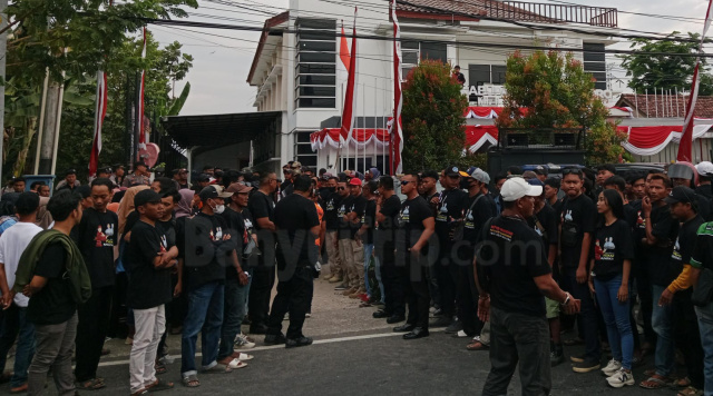 Para pendekar silat berkaos serba hitam membentuk barikade di gedung KPU Bojonegoro.